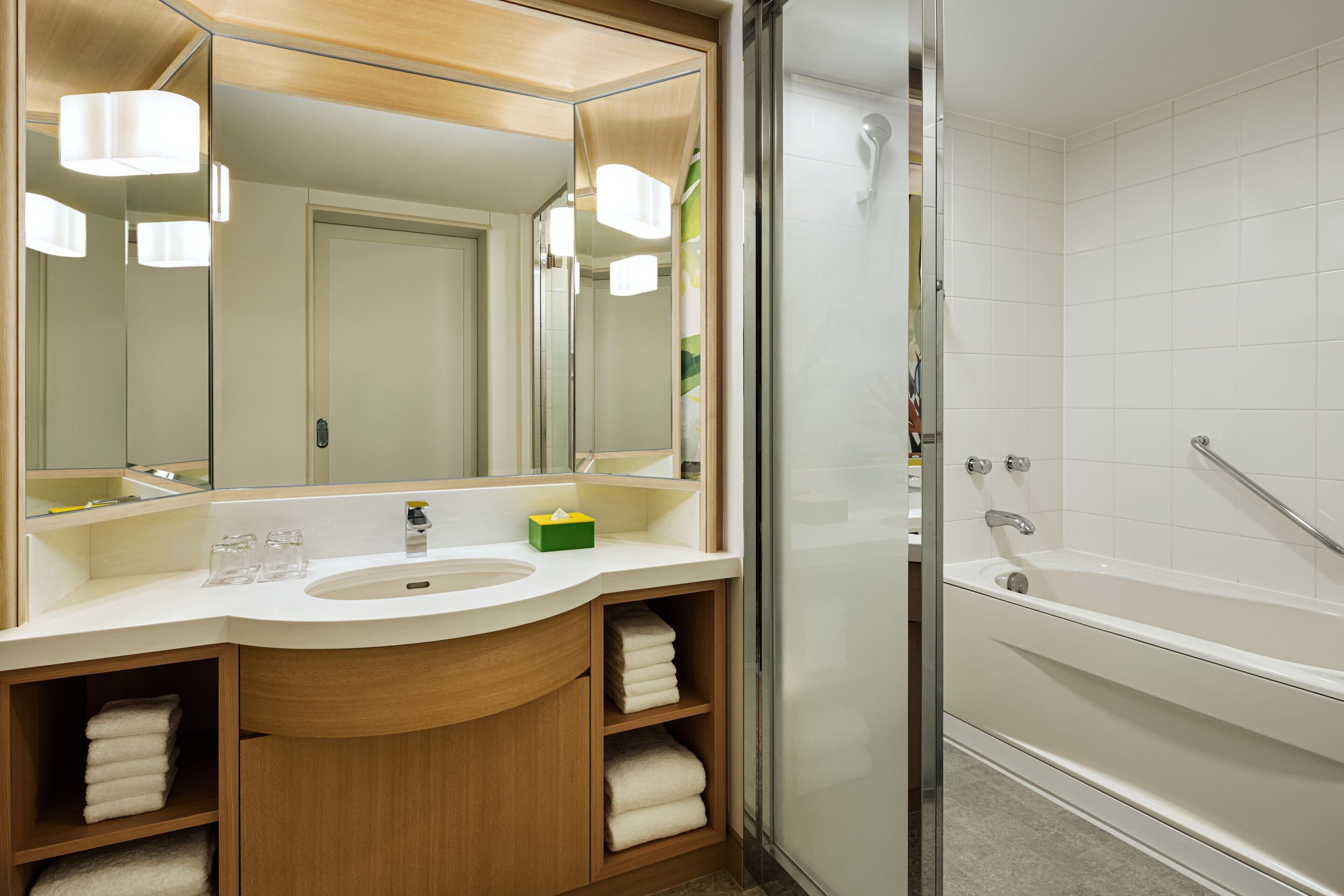 A modern bathroom with a large mirror, a sink, a bathtub, and a glass shower enclosure.
