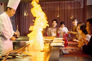 A restaurant with a chef performing a flambé.