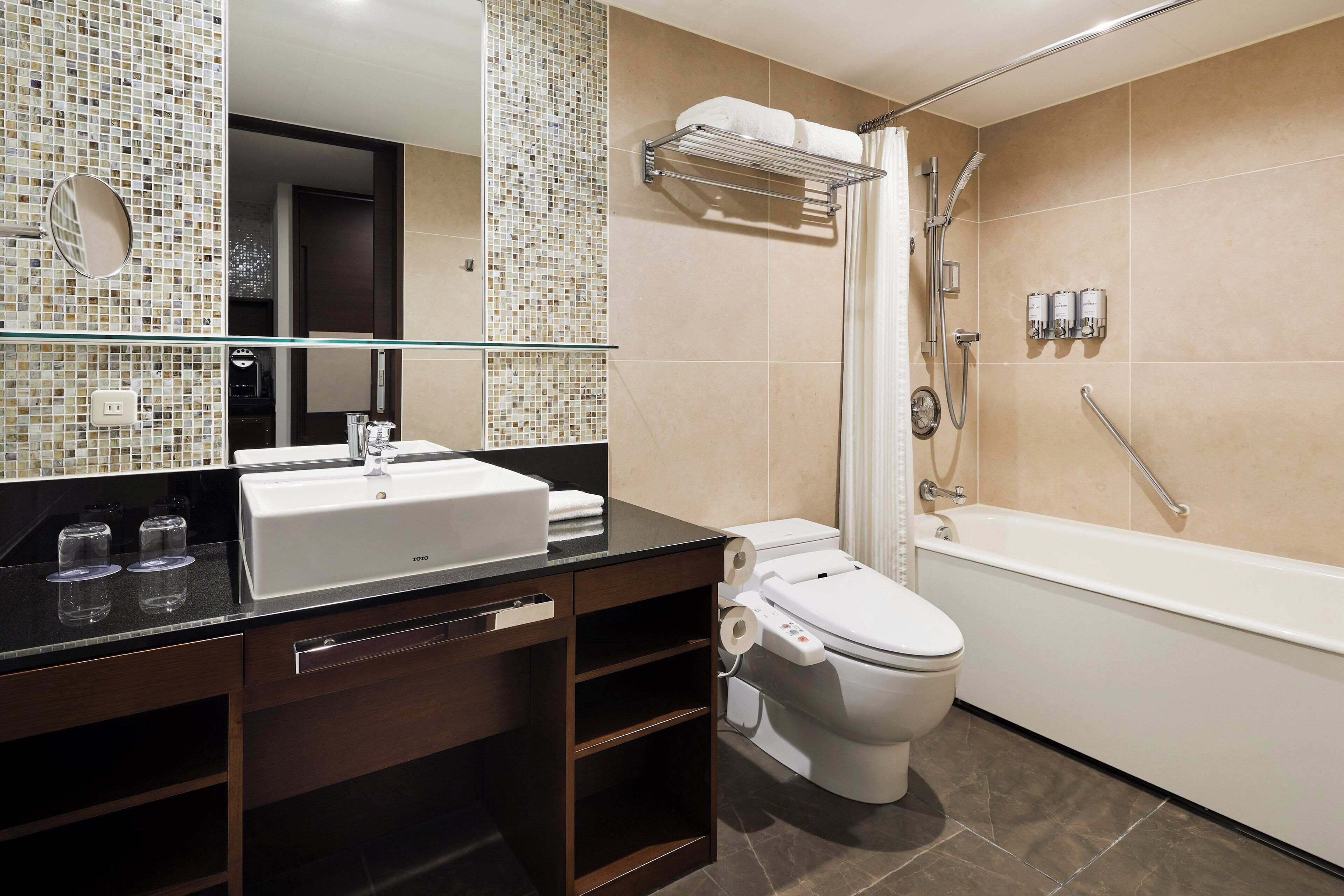 A modern bathroom with a glass shower enclosure, a white toilet, and a black vanity with a mirror.