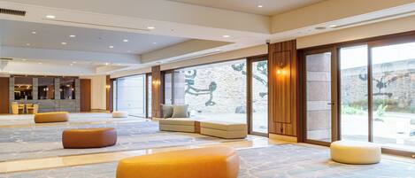 A spacious lobby with a large seating area, a reception desk, and a view of the outdoors through large glass doors.