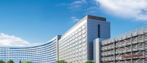 A modern hotel with a curved facade, multiple floors, and a prominent Sheraton sign.