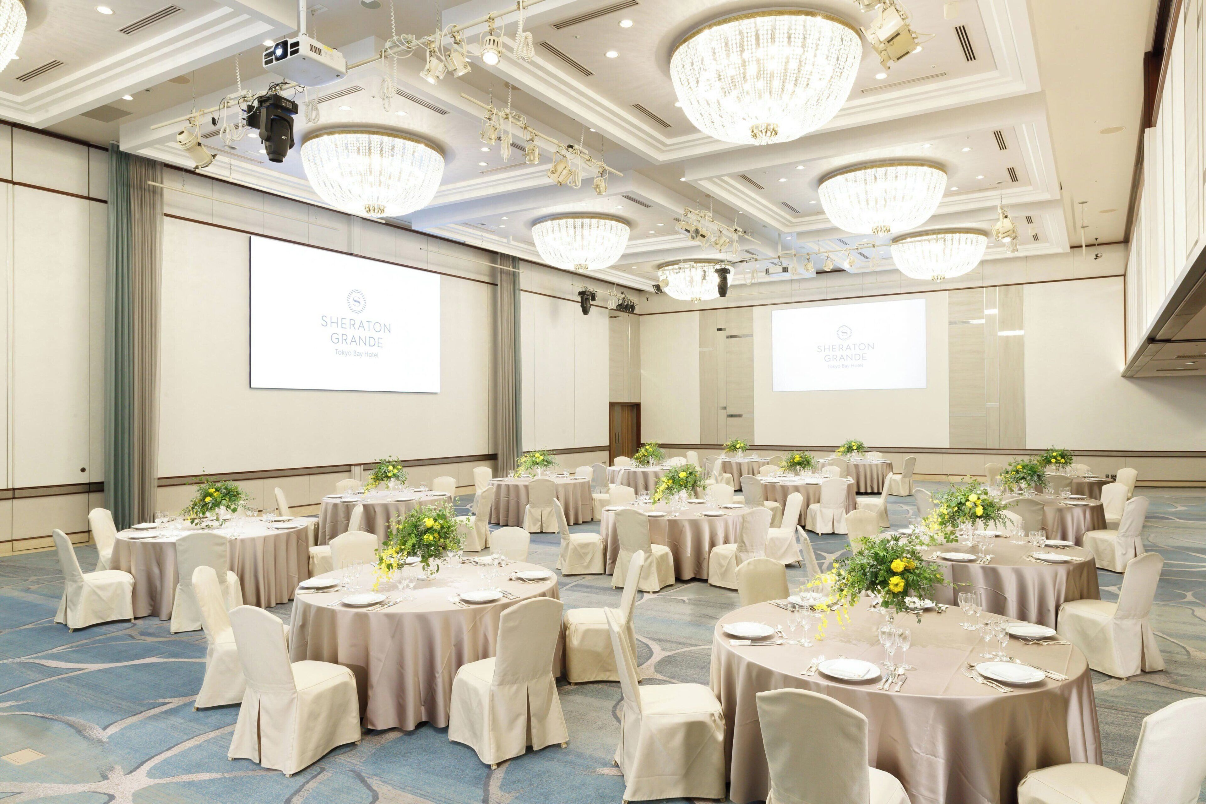A conference room at Sheraton Grande Tokyo Bay Hotel with multiple round tables, beige tablecloths, and white chairs.