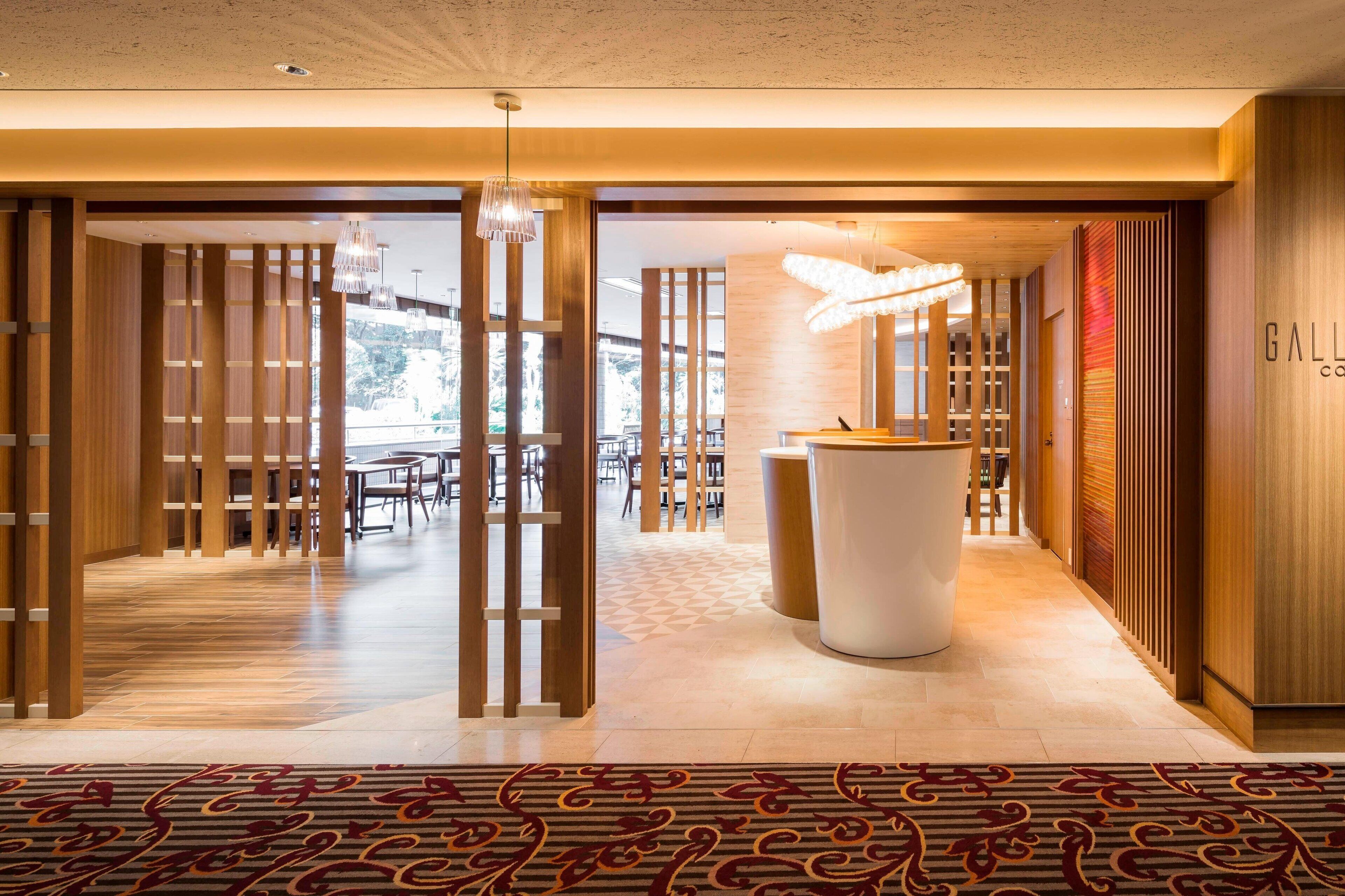 A modern hotel lobby with a reception desk, wooden paneling, and a patterned carpet.