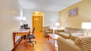 A hotel room with a wooden desk, two armchairs, a sofa, a lamp, and a wall-mounted artwork. - Econo Lodge Inn & Suites Albuquerque East I-40 Eubank Exit (Albuquerque)