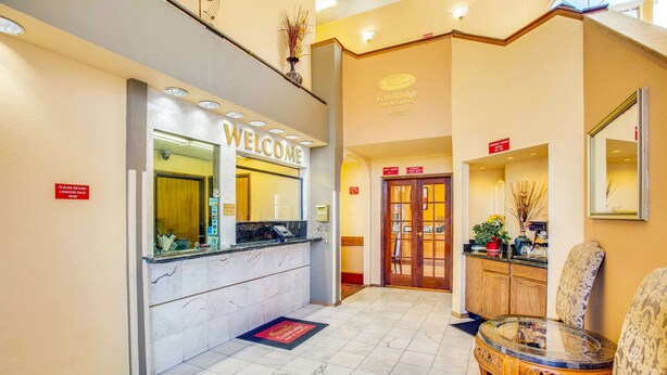A hotel reception area with a 'WELCOME' sign, a reception desk, a waiting area with a round table and chairs, and a 'Luggage Rack' sign. - Econo Lodge Inn & Suites Albuquerque East I-40 Eubank Exit (Albuquerque)