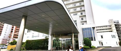Um edifício moderno com marquise de entrada curva, janelas amplas e fachada de vidro.