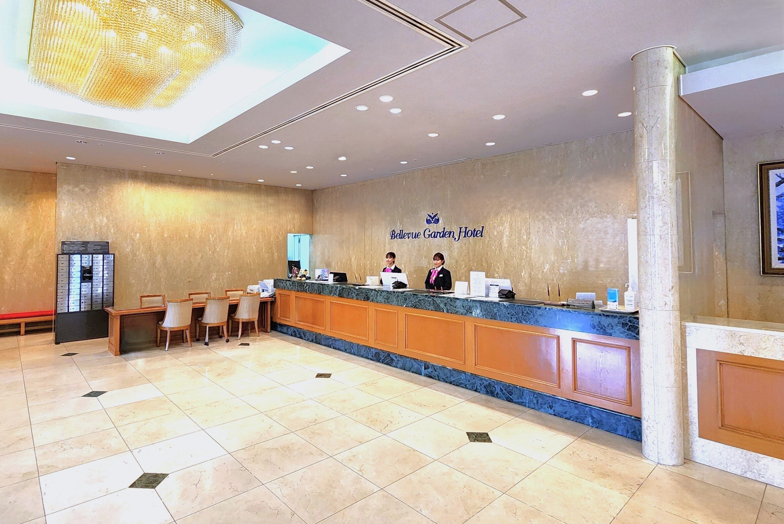 A hotel reception area with a marble counter, reception desk, and seating area.