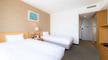 A hotel room with two beds, a nightstand with a lamp, a painting on the wall, and a door leading to a hallway.