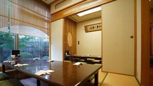 Un salón de conferencias con una larga mesa, sillas y piso de esteras de tatami.