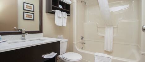 A bathroom with a sink, toilet, and bathtub. There are towels hanging on the wall and a shower curtain.