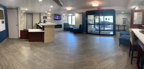A spacious lobby with a reception desk, seating area, and a glass door entrance.