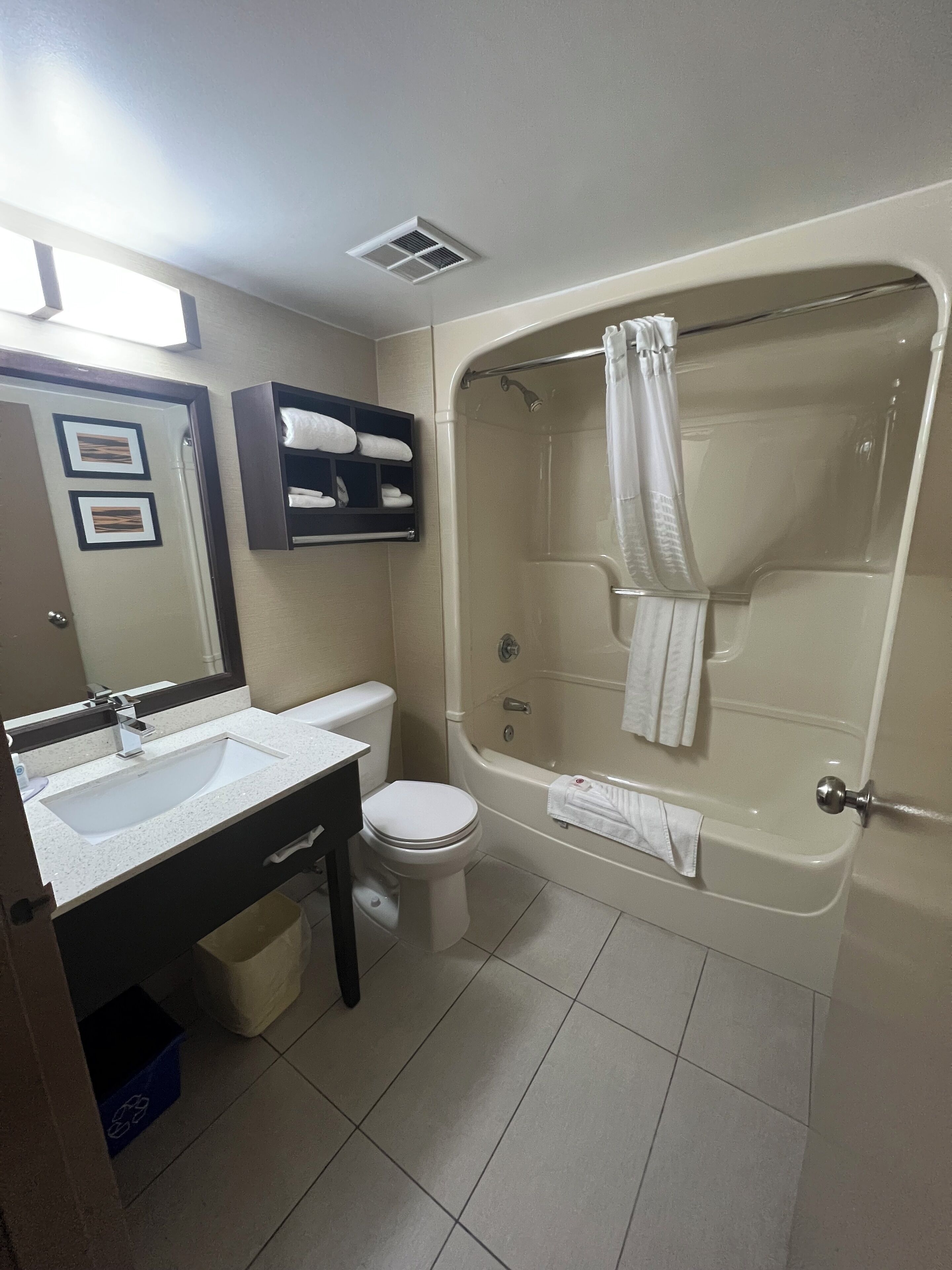 Un baño con bañera, inodoro, lavamanos y toallero.