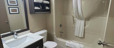 Un baño con bañera, inodoro, lavamanos y toallero.