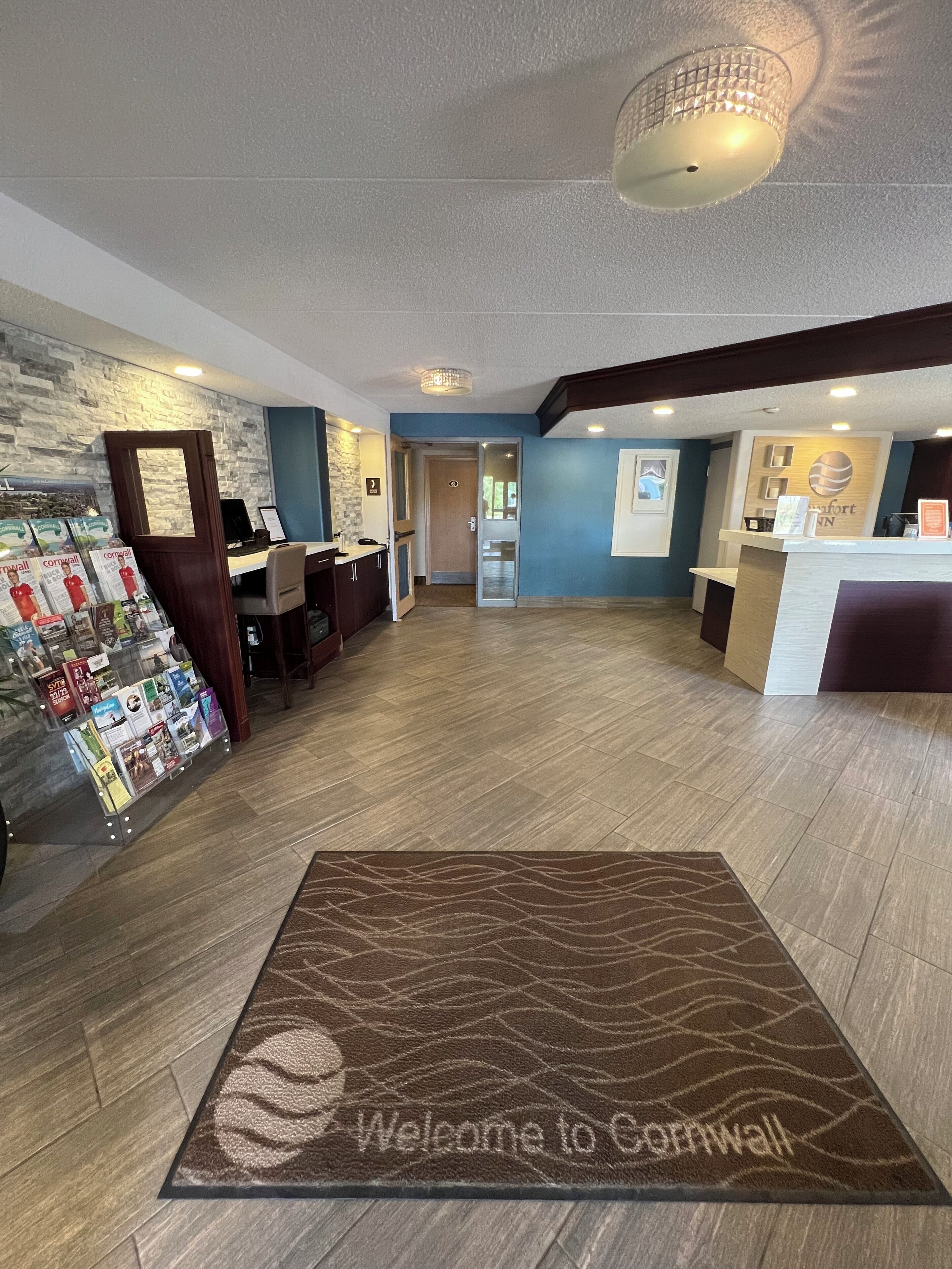 A reception area with a wooden reception desk, a magazine rack, and a welcome mat.