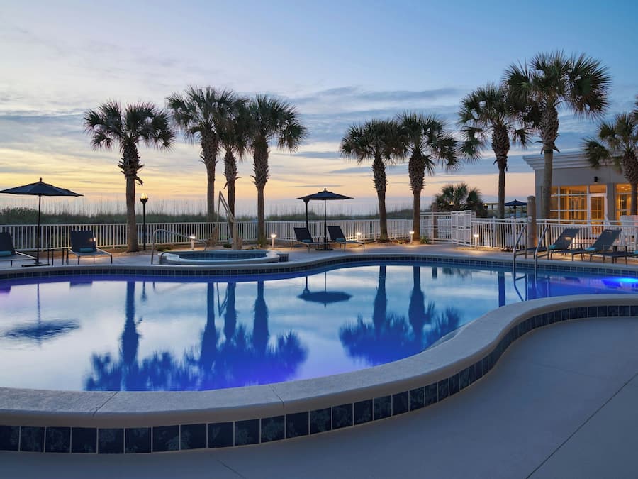 Una piscina al aire libre, sombrillas, sillones reclinables de piscina