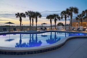 Una piscina al aire libre, sombrillas, sillones reclinables de piscina