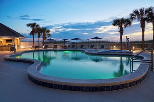 Una piscina al aire libre, sombrillas, sillones reclinables de piscina