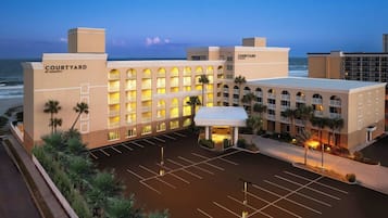 Een Courtyard by Marriott hotel met een ruime parkeerplaats, meerdere balkons en uitzicht op de oceaan.