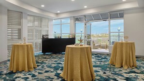 A room with three round tables, a black bar, and large windows with a view.