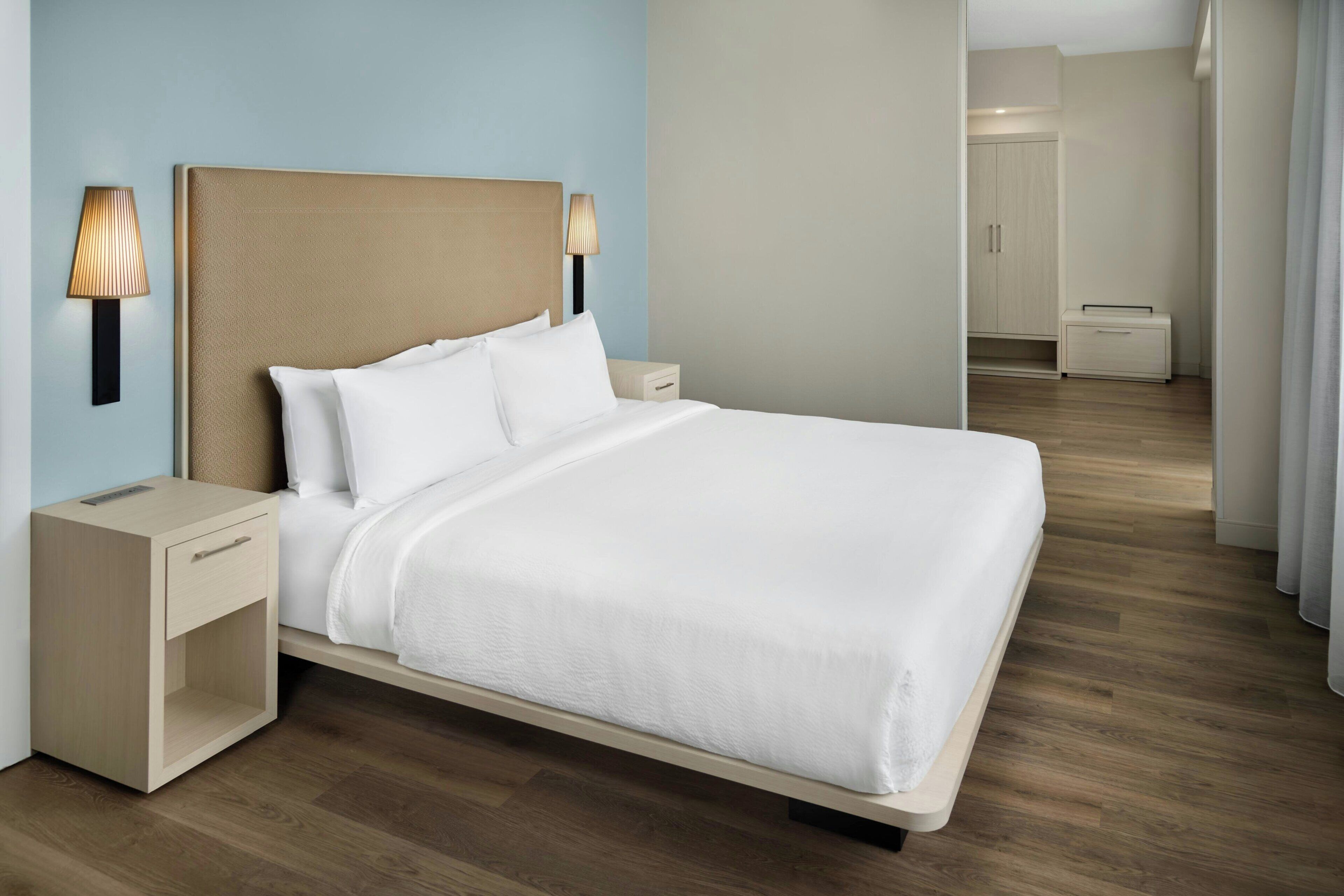 Une chambre d’hôtel moderne, dotée d’un grand lit, de tables de chevet et d’une armoire.