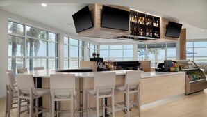 A modern bar area with a high counter, bar stools, and a beverage dispenser.