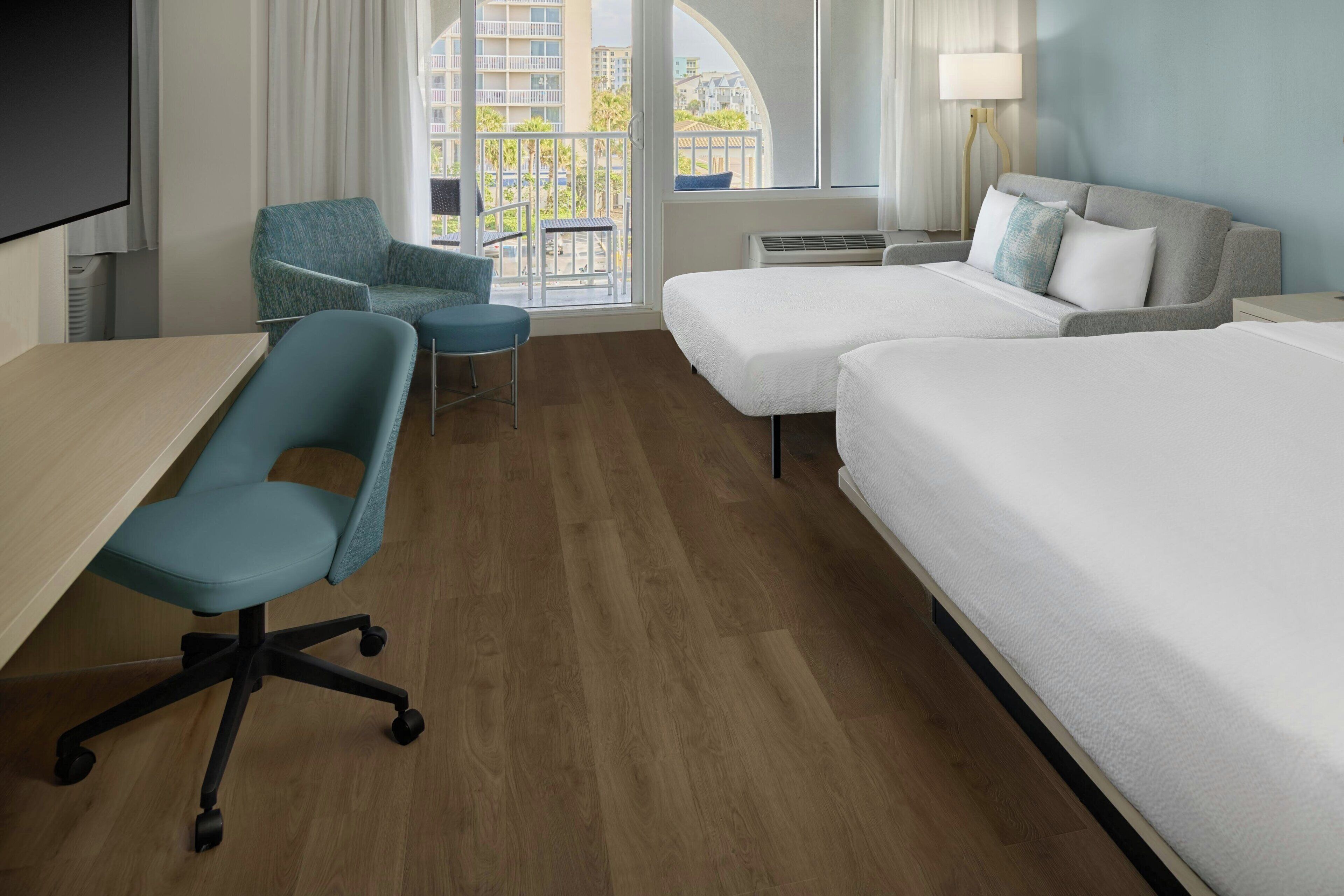 Habitación de hotel con escritorio, dos sillas, una cama y vistas a la ciudad.