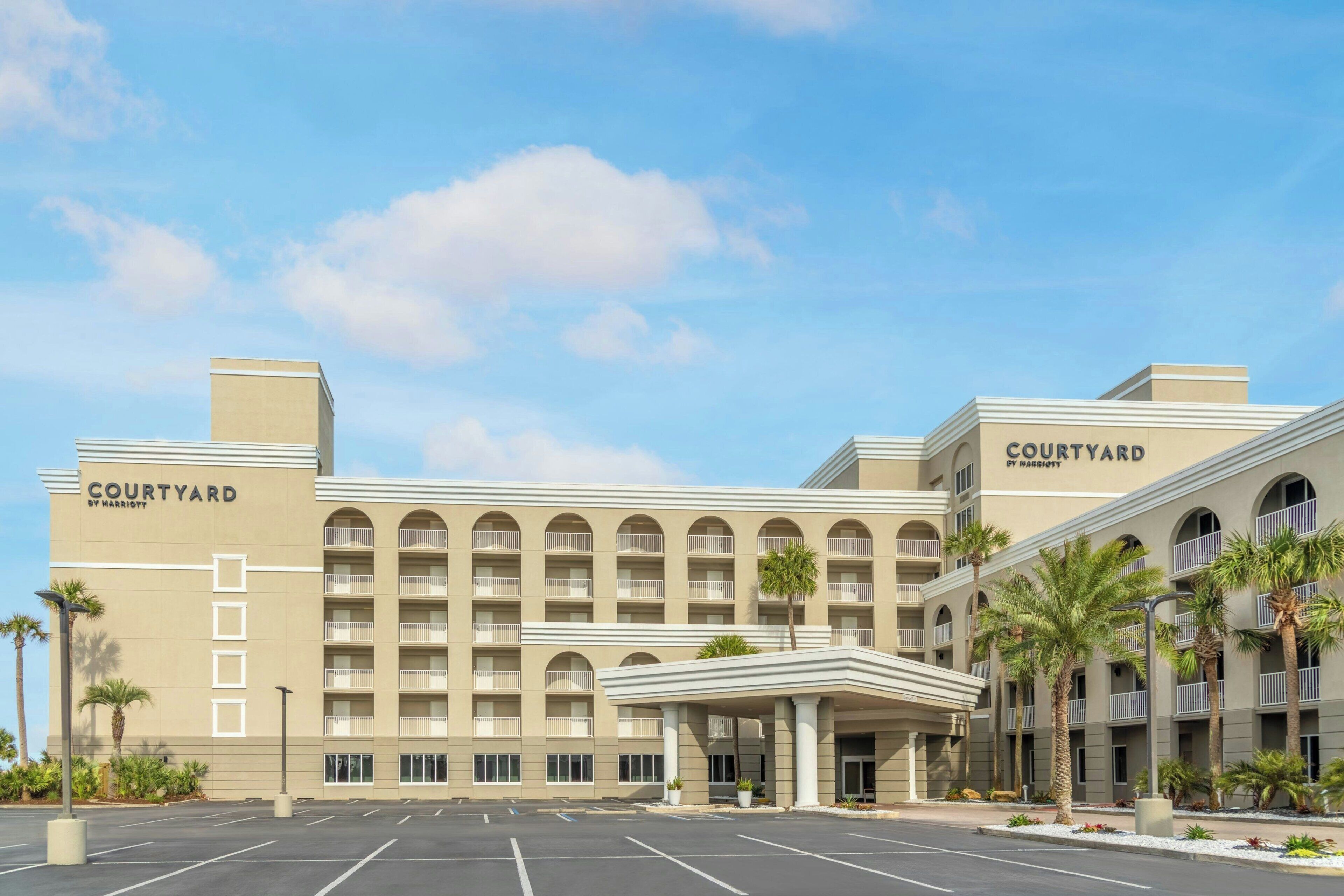 Un hotel Courtyard by Marriott con una fachada simétrica, varios balcones y una entrada central.