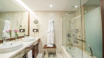 Un baño moderno con dos lavamanos, un espejo grande, cabina de ducha de vidrio y un taburete de madera.