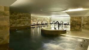 A spa area with a hot tub, lounge chairs, and stone walls. - Porto Palácio Hotel by The Editory (Porto)