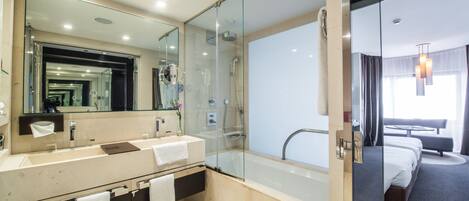 A modern bathroom with a glass-enclosed shower, a large mirror, and a bathtub.