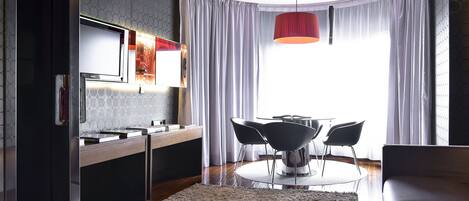 A modern kitchen with a built-in oven, a dining area with a round table and four chairs, and a large window with curtains.