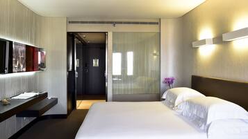 Una habitación de hotel con una cama, un escritorio, un espejo y una puerta que da a un baño.