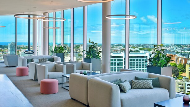 A modern lounge with large windows, white sofas, and potted plants. - Porto Palácio Hotel by The Editory (Porto)