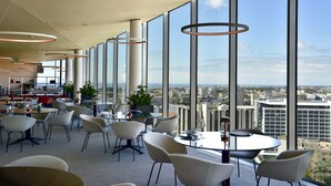 A modern dining area with large windows, white chairs, and a city view. - Porto Palácio Hotel by The Editory (Porto)