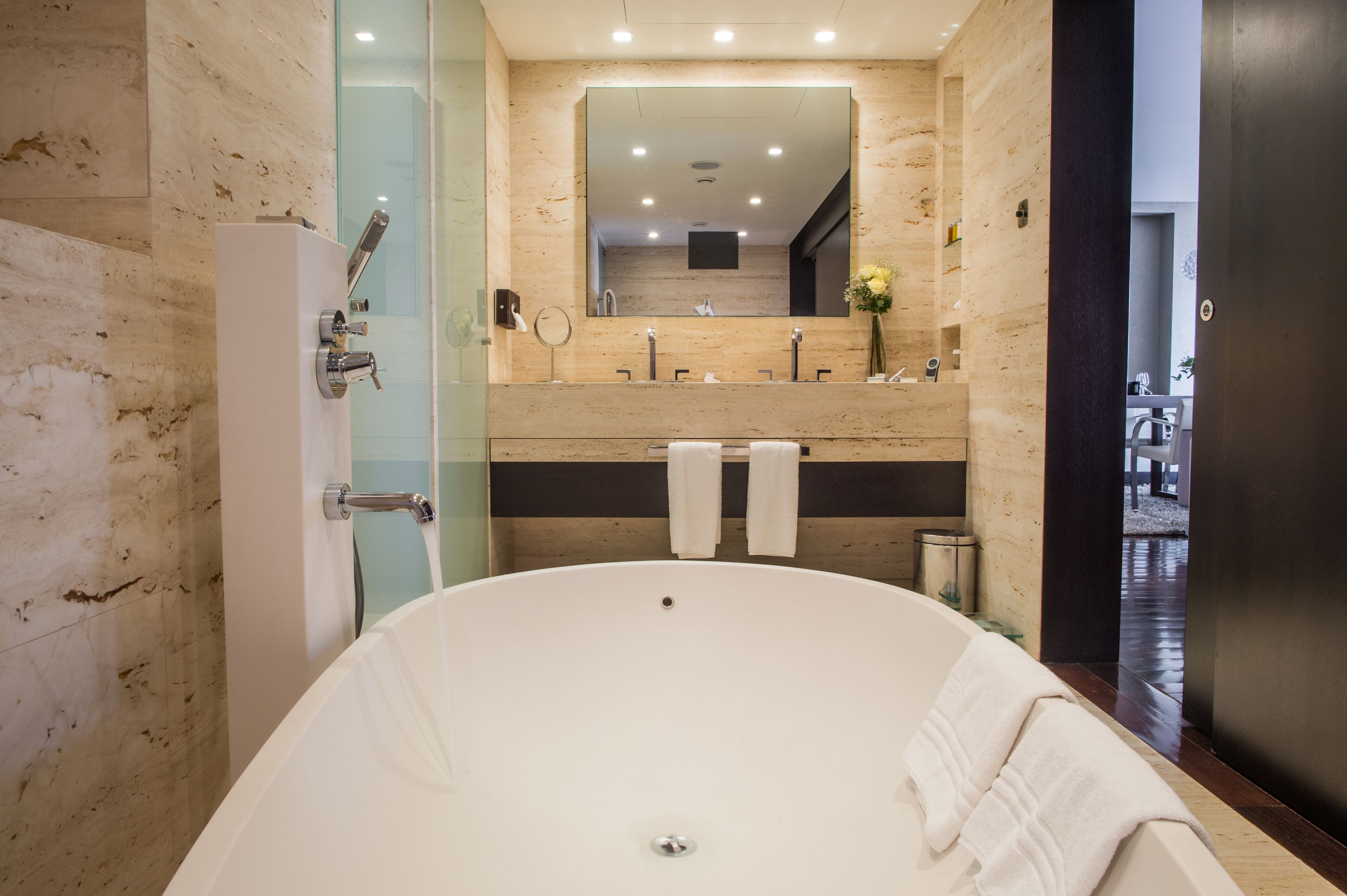 Une salle de bain moderne avec une baignoire sur pieds, un grand miroir et un meuble-lavabo doté de deux vasques.