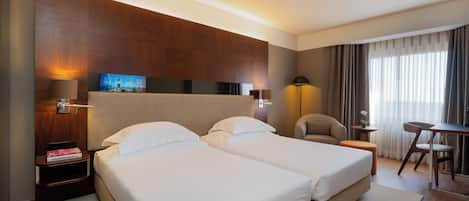 Une chambre d’hôtel avec deux lits, un bureau, une chaise, une télévision et une lampe.