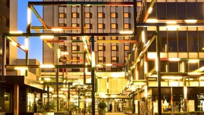 A high-rise hotel with multiple floors, a prominent glass facade, and a well-lit entrance area. - Porto Palácio Hotel by The Editory (Porto)