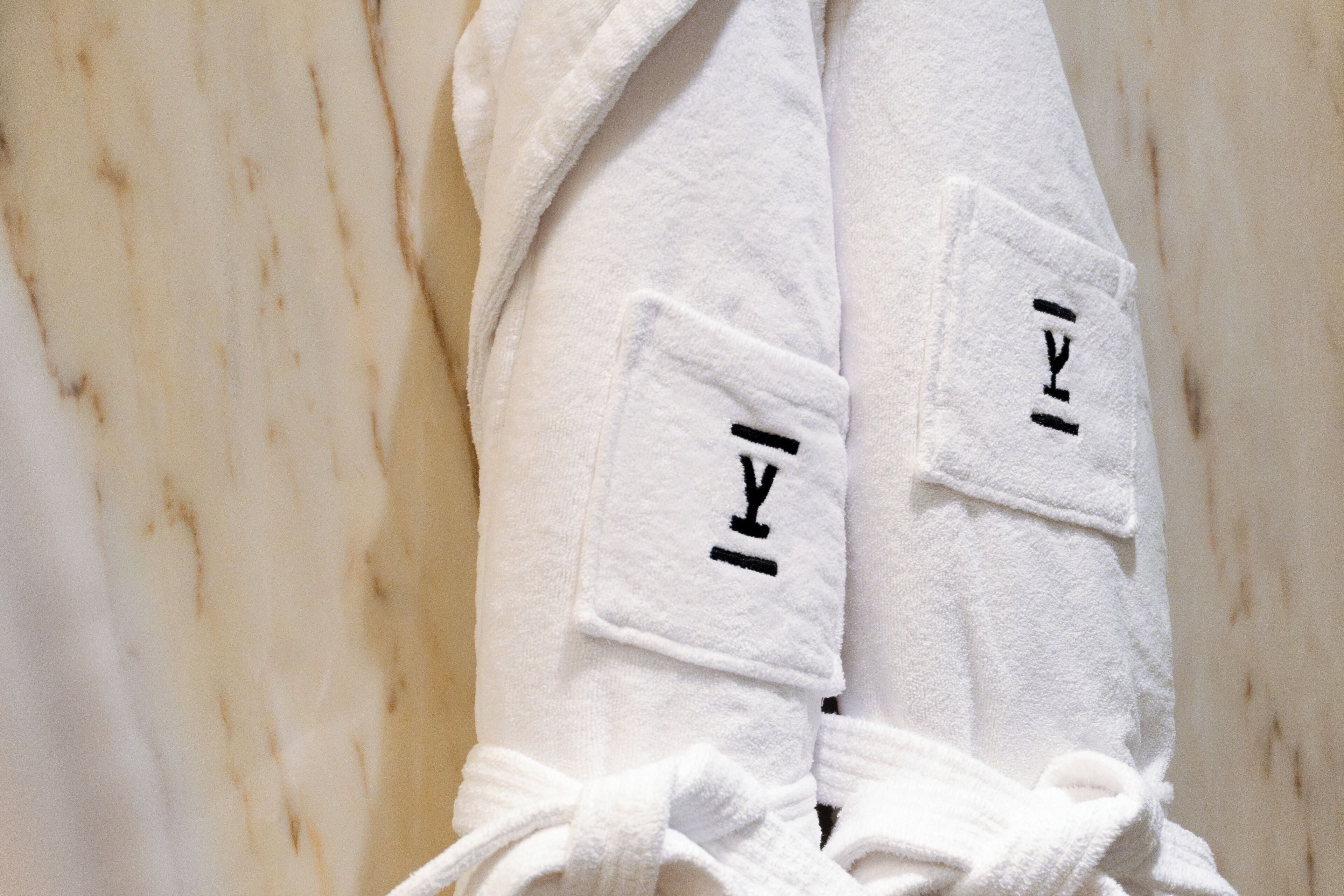 A pair of white towels with black text on a marble surface.