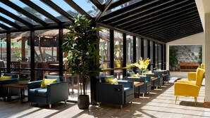 A spacious indoor area with a glass ceiling, modern seating arrangements, and a large potted plant. - Four Points by Sheraton Anaheim (Anaheim)