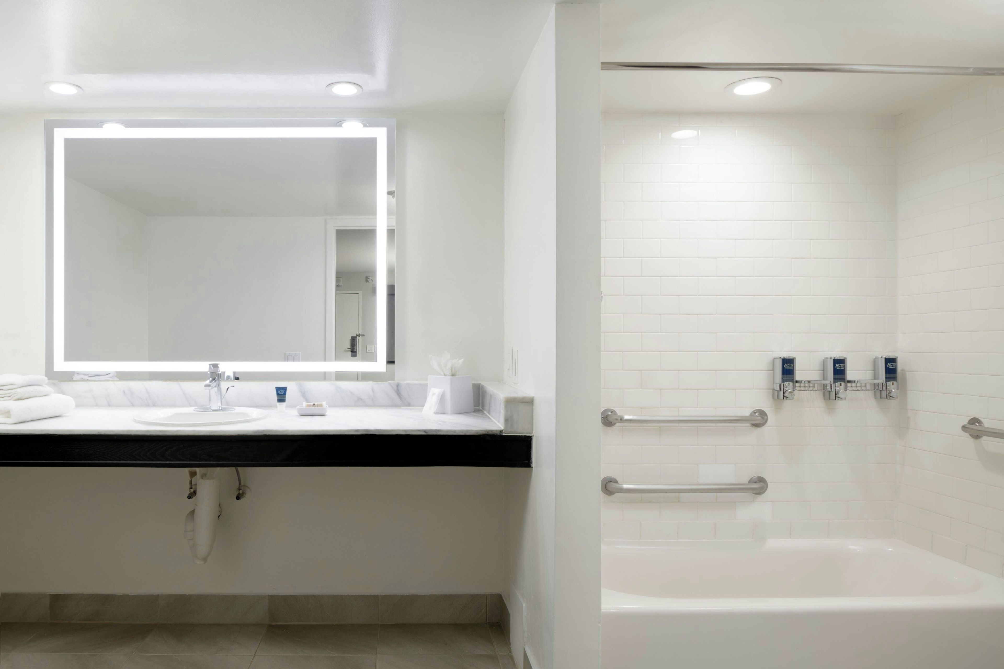 Un baño moderno con un lavamanos, espejo y bañera blancos.