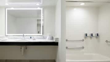 Un baño moderno con un lavamanos, espejo y bañera blancos.