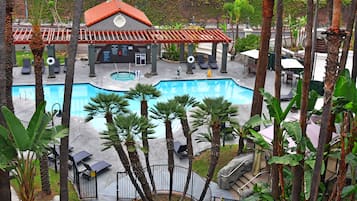 A swimming pool with lounge chairs, a lifeguard tower, and a covered seating area.