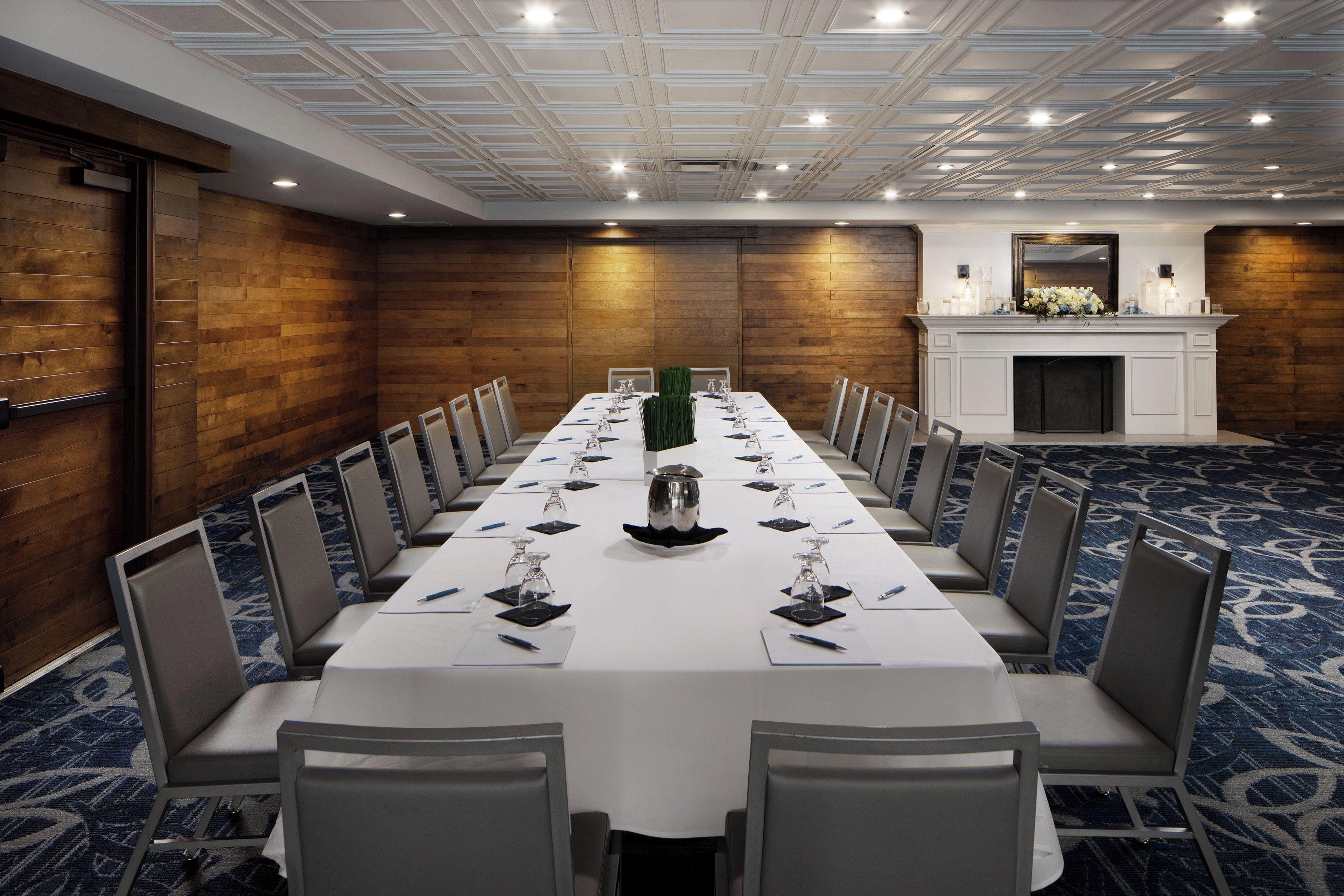 A conference room with a long table, chairs, and a fireplace.