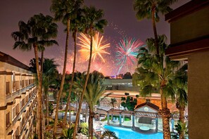 A hotel with a pool, palm trees, and fireworks in the background. - Four Points by Sheraton Anaheim (Anaheim)