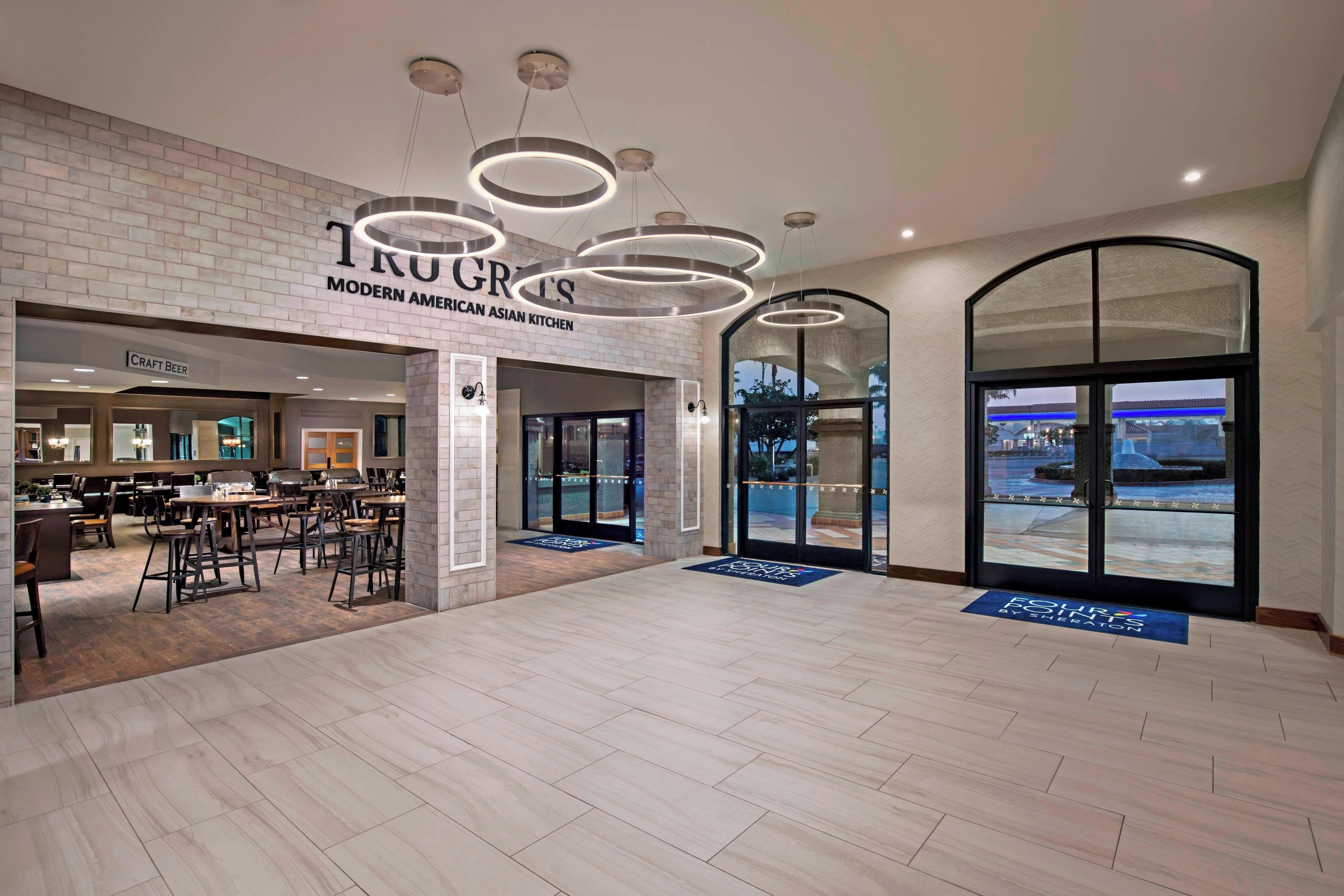 A spacious indoor area with a modern American Asian kitchen and craft beer bar, large windows offering a view, and a wooden floor.