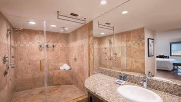 A modern bathroom with a glass-enclosed shower, a granite countertop, and a large mirror.