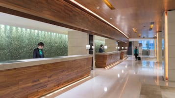 Een moderne receptie met houten balies en een groene wand.