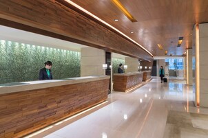Una moderna zona de recepción con mostradores de madera y una pared verde.