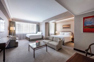 A hotel room with a bed, a sofa, a desk, and a chair.