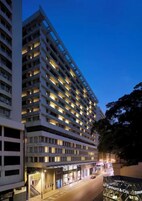 A multi-story hotel with illuminated windows, a ground-level entrance, and a storefront with a sign.
